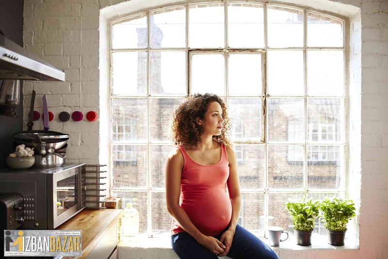 زن باردار نشسته لب پنحره